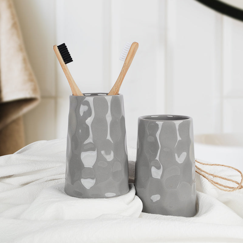 Close-up of the grey BosilunLife Bring Nature Inside recycled eco-clay tumblers holding bamboo toothbrushes on a white bathroom towel.