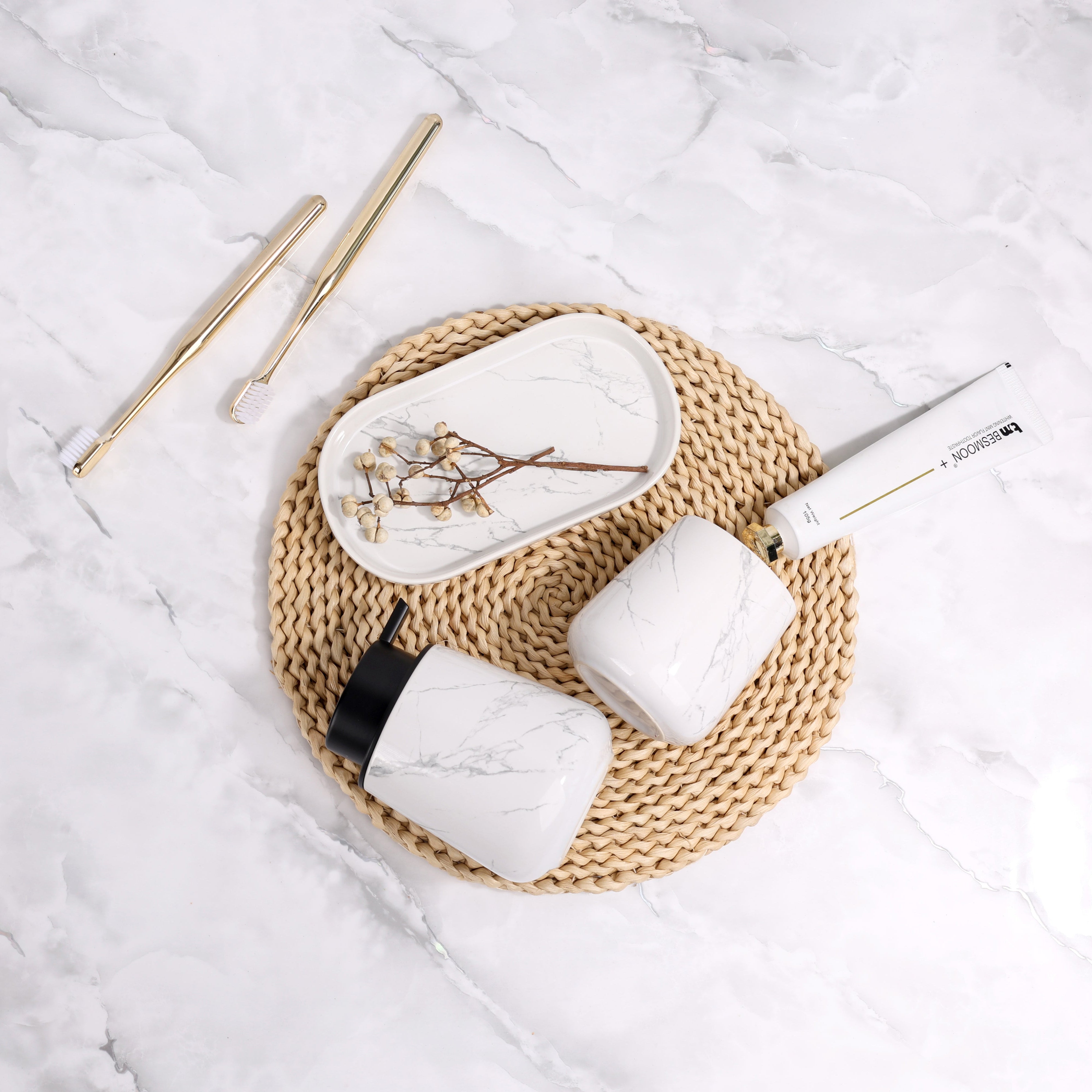 White ceramic cups with gold handles on a woven mat on a marble surface