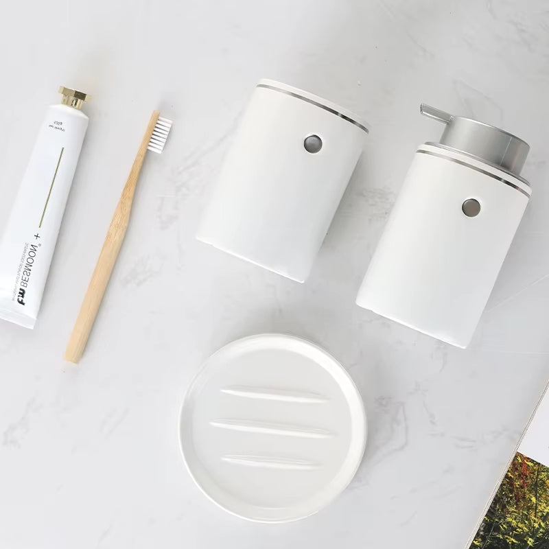 Set of white bathroom products including a toothbrush, toothpaste, and containers on a light surface.