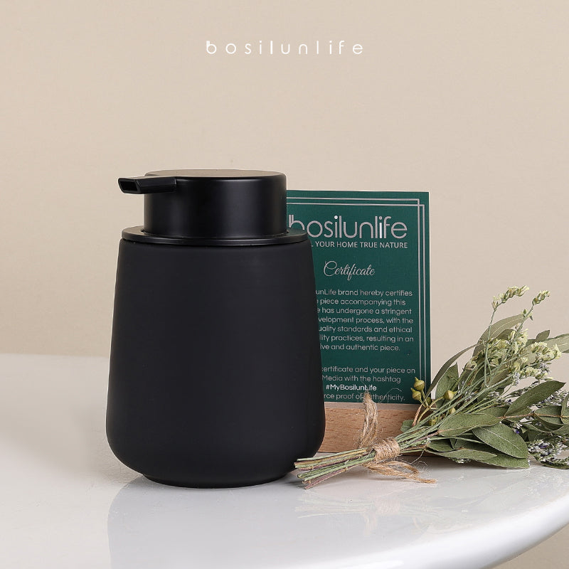 Product hero shot of the BosilunLife 12 oz Charcoal Grey Rubber Paint Foaming Soap Dispenser with a matte black pump. It is styled on a textured concrete surface alongside a botanical sprig and an official Certificate of Authenticity. This composition provides visual 'Trust Signals' regarding its premium quality and verified GRS certified recycled material origin.