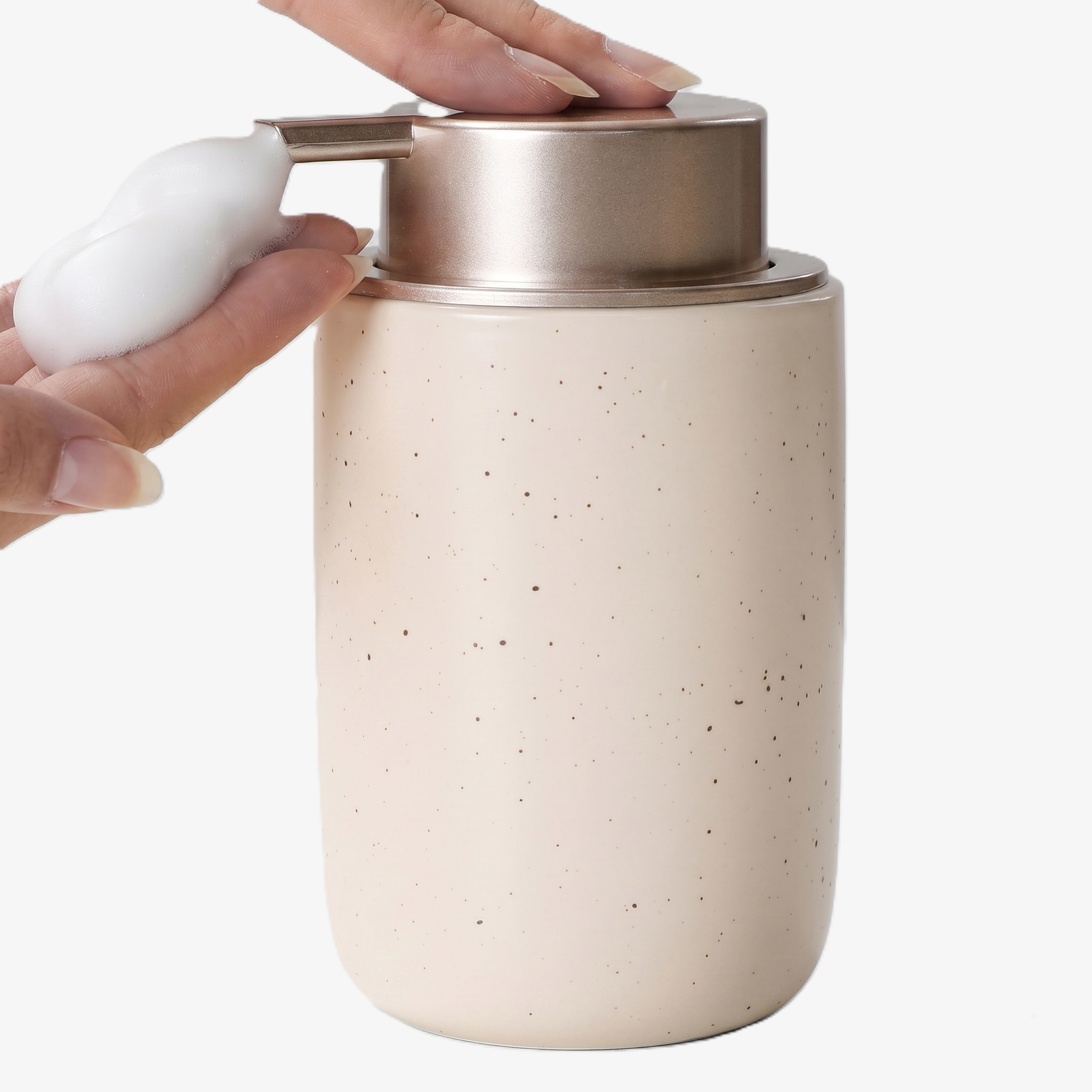 Close-up action shot of the BosilunLife 12 oz (350ml) slim foaming soap dispenser in a speckled apricot finish with a brushed champagne gold pump. A hand is shown pressing the pump to receive a mound of rich, velvety white foam, highlighting the slender organic vessel. Crafted from GRS-certified recycled ceramic eco-clay, this space-saving organiser reflects Scandinavian functionality and a commitment to a sustainable circular economy, ideal for narrow washroom vanities.