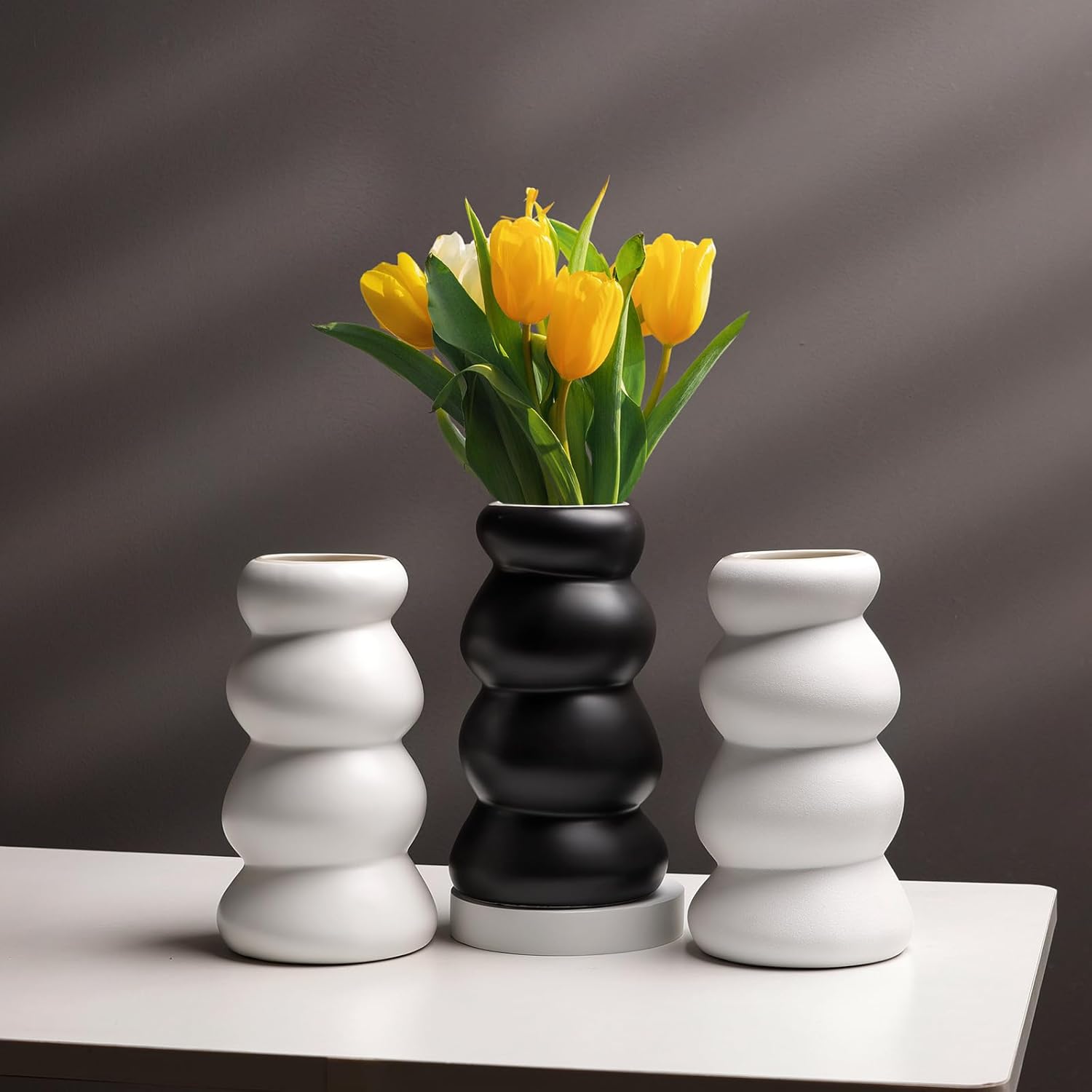 Three modern vases with a black and white striped pattern on a gray background