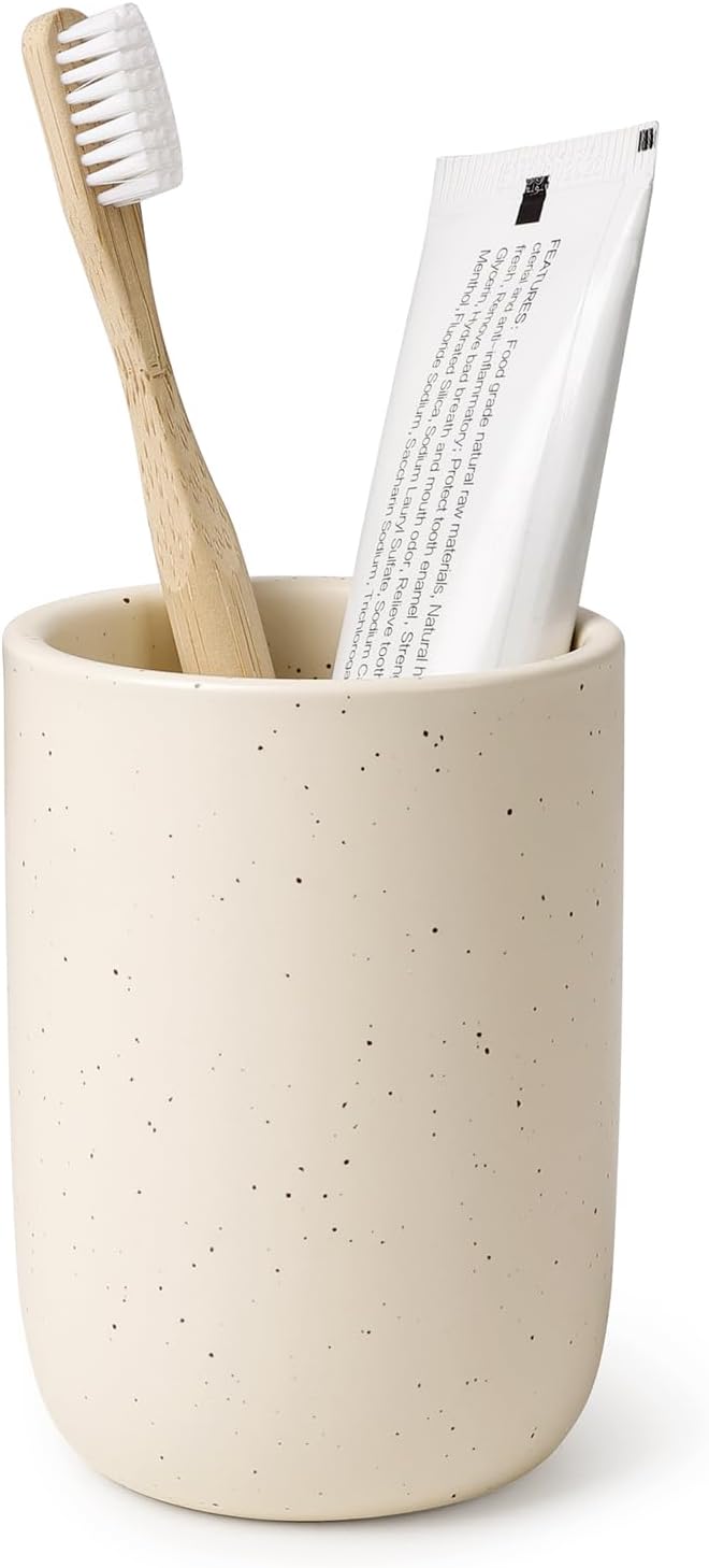 BosilunLife eco-luxury bathroom tumbler and toothbrush holder in a speckled sand finish. Crafted from GRS-certified recycled ceramic eco-clay, the piece features an organic rounded silhouette that balances Scandinavian functionality with the quiet harmony of nature. Styled with a sustainable bamboo toothbrush and white toothpaste tube, it showcases intentional design and a commitment to a circular economy and a sustainable world.