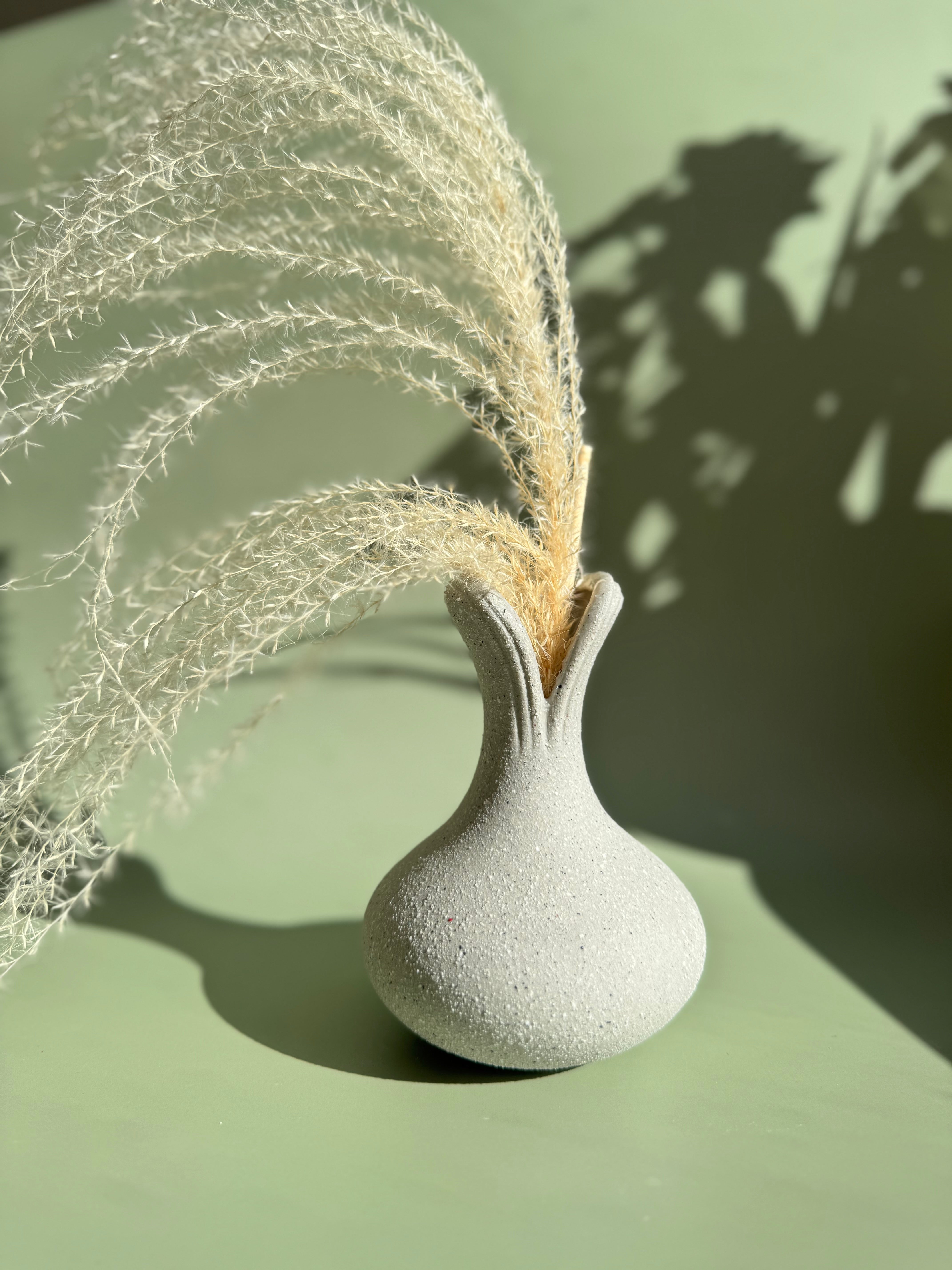 BosilunLife recycled eco-clay ceramic vase holding dried decorative grass against a light green background with natural plant shadows.
