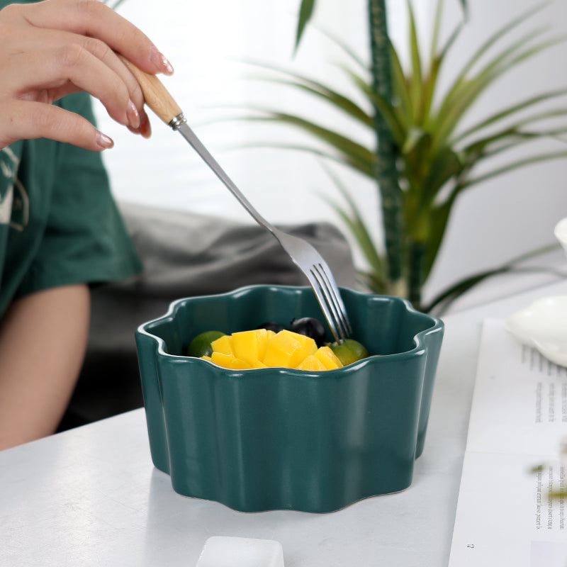 A green bowl with fruit in it.