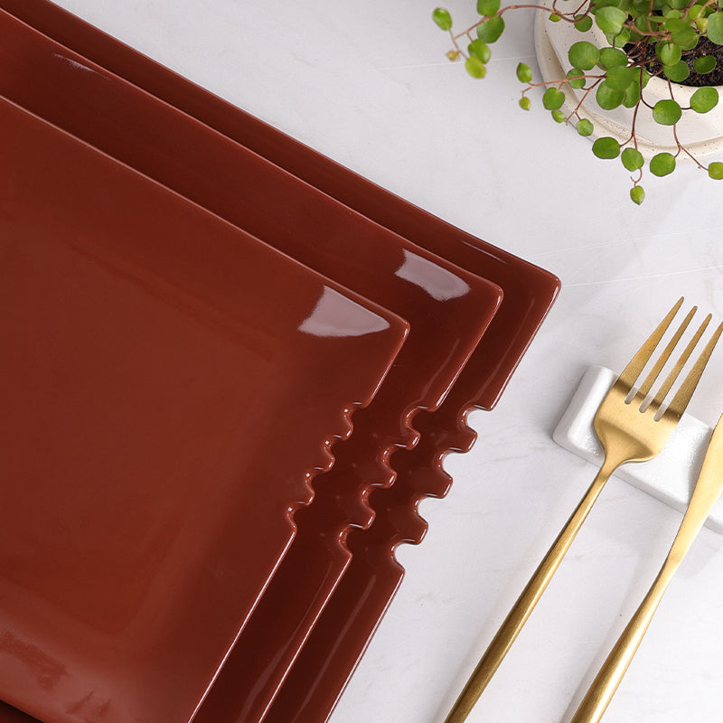 Detail of a square ceramic dinner plate in brownish red