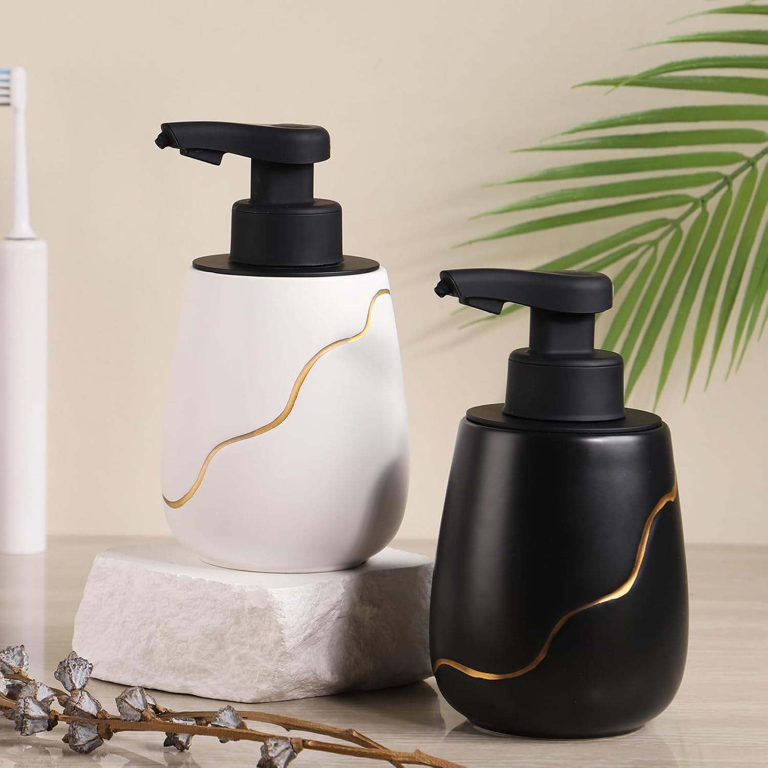 Two soap dispensers, one white and one black, with gold accents on a neutral background.