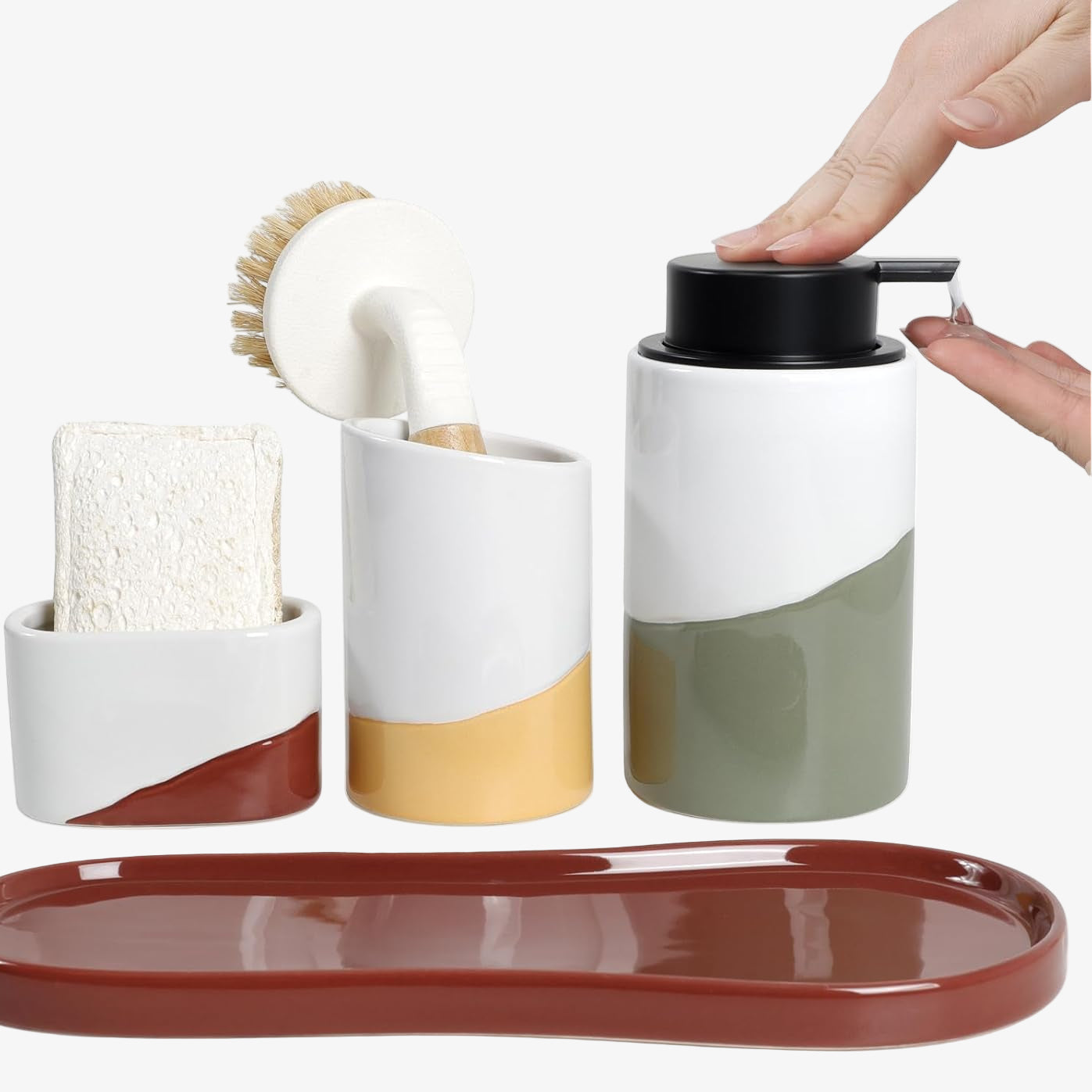 BosilunLife Waves 4-piece kitchen sink caddy set in recycled eco-clay. The vibrant collection features a terracotta tray, a white and terracotta sponge holder containing a natural sponge, a white and mustard yellow brush holder with a wooden dish brush, and a white and sage green liquid soap dispenser. A person's hands press the manual black pump to dispense clear dish soap, highlighting colourful and functional kitchen sink organisation.
