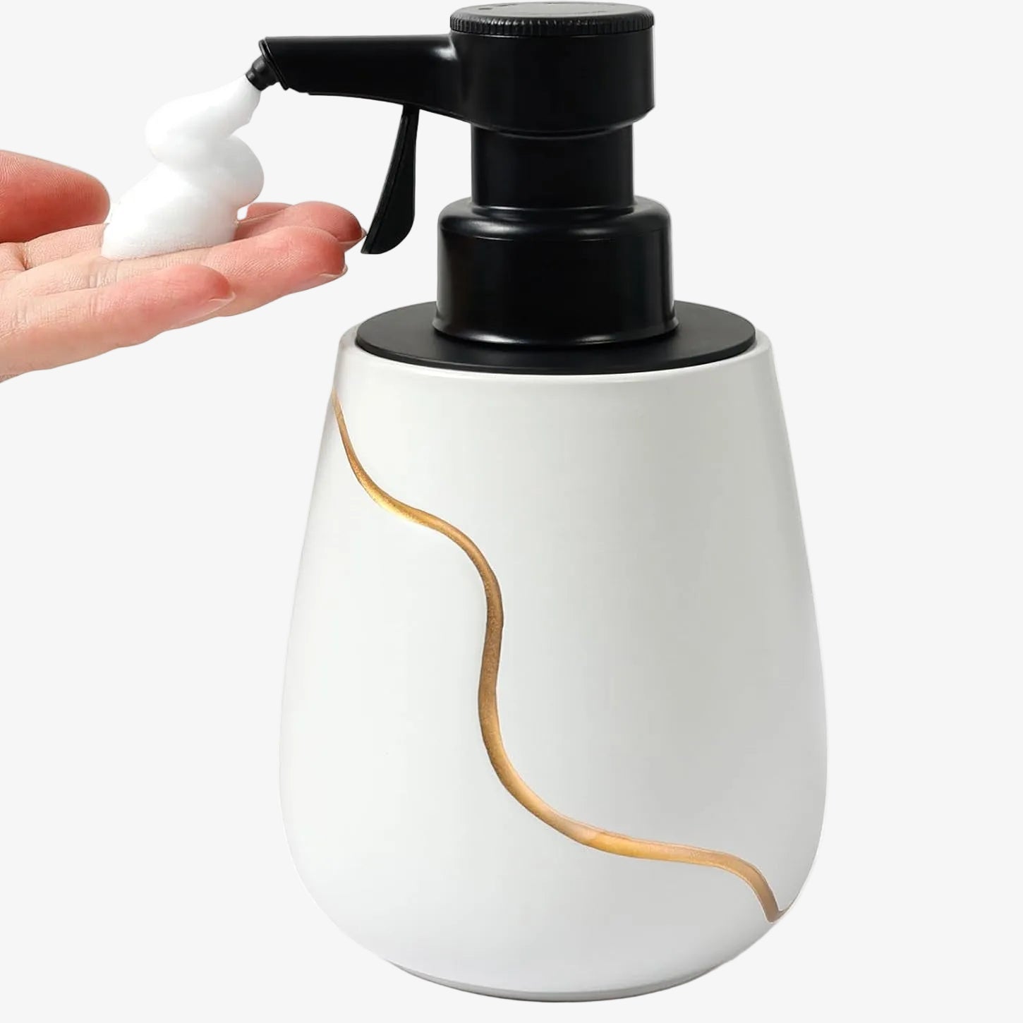 A hand receiving thick white foam from the 18.94 oz BosilunLife Nordic Garden semi-automatic foaming dispenser. The white recycled eco-clay ceramic bottle features an elegant gold wave design and a black USB-rechargeable manual press pump.