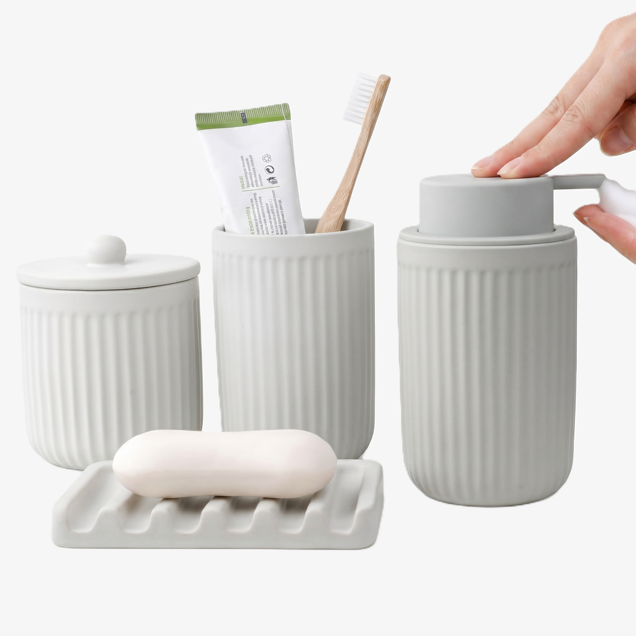 A 4-piece BosilunLife Pockmark bathroom set made of speckled white recycled eco-clay. The collection includes a foaming soap dispenser with a black pump, a ribbed toothbrush holder, a lidded ceramic storage jar, and a sculptural wave-patterned soap dish holding a bar of soap.