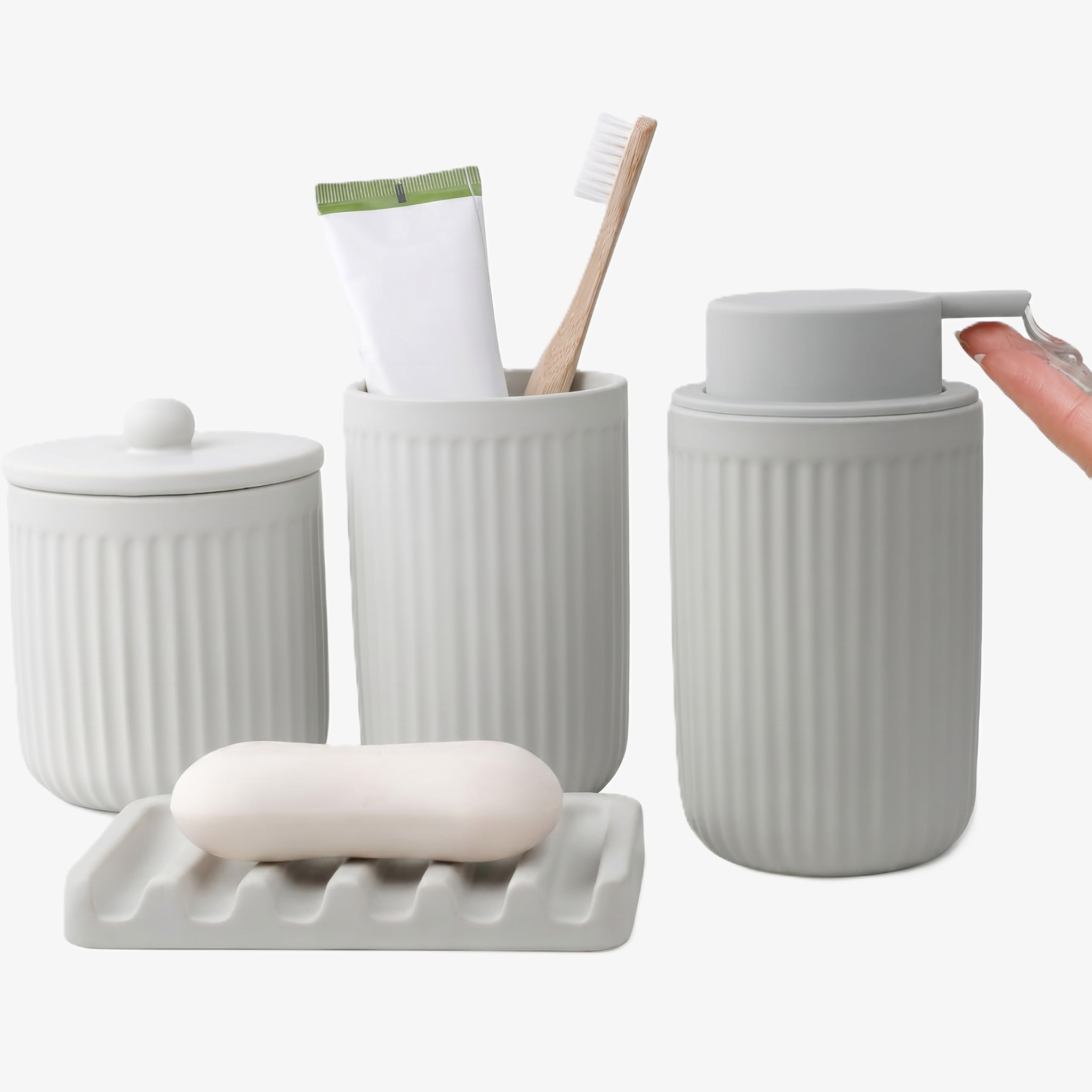 A comprehensive 4-piece BosilunLife bathroom organisation set in a monochromatic matte fluted grey finish, crafted from GRS-certified recycled ceramic eco-clay. The ensemble features a ribbed tumbler styled with a wooden toothbrush and toothpaste, a coordinating lidded storage jar, a wavy-ridged soap dish holding an oval bar of soap, and a fluted liquid soap dispenser, showing a hand dispensing clear liquid from the perfectly matched grey wide-head pump.