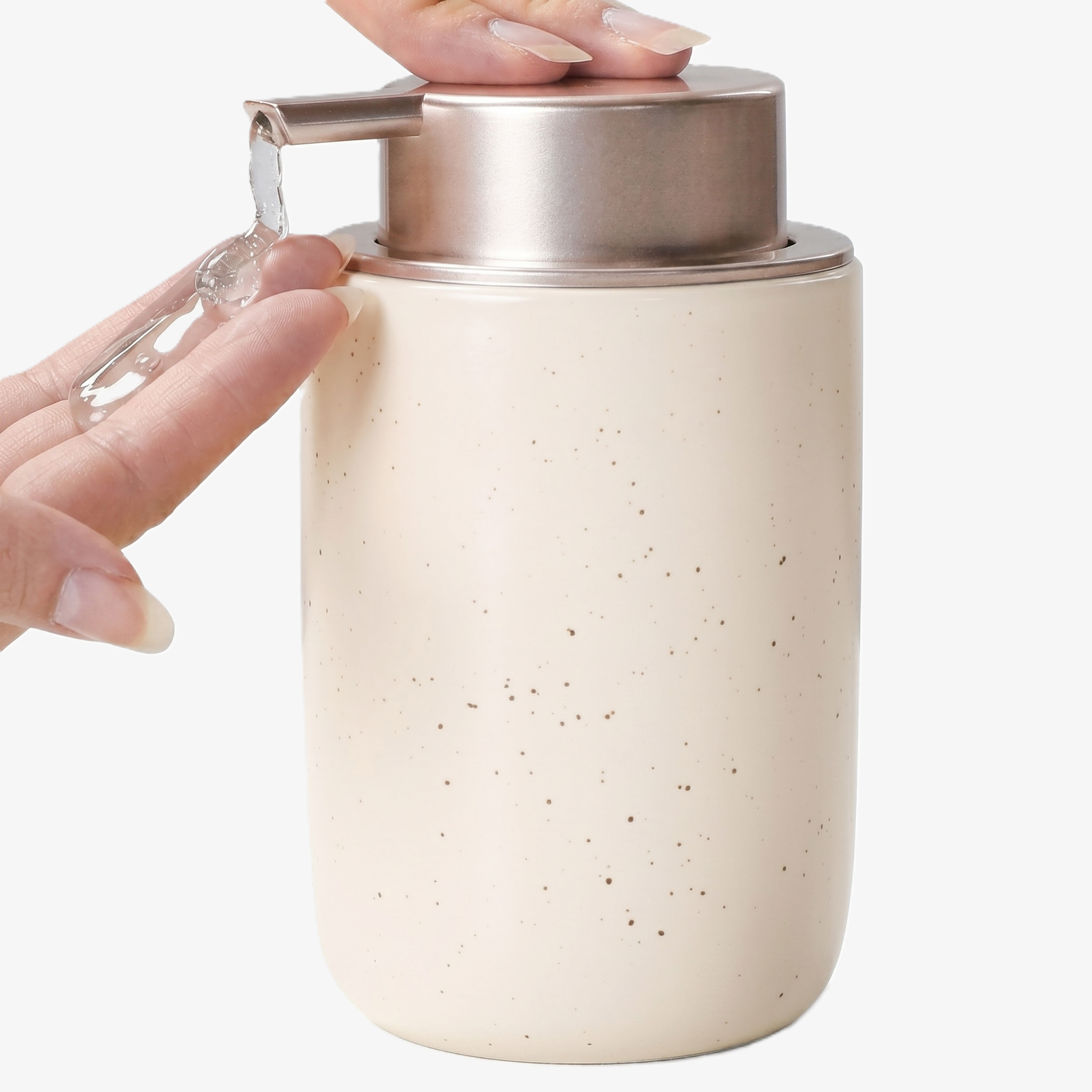Close-up action shot of the BosilunLife 12 oz (350ml) slim liquid soap dispenser in a speckled 'Apricot Cream' finish with a brushed champagne gold pump. A hand is shown pressing the pump to dispense clear liquid, highlighting the slender organic vessel. Crafted from GRS-certified recycled ceramic eco-clay, this space-saving organiser reflects Scandinavian functionality and a commitment to a sustainable circular economy, perfect for narrow washroom vanities.