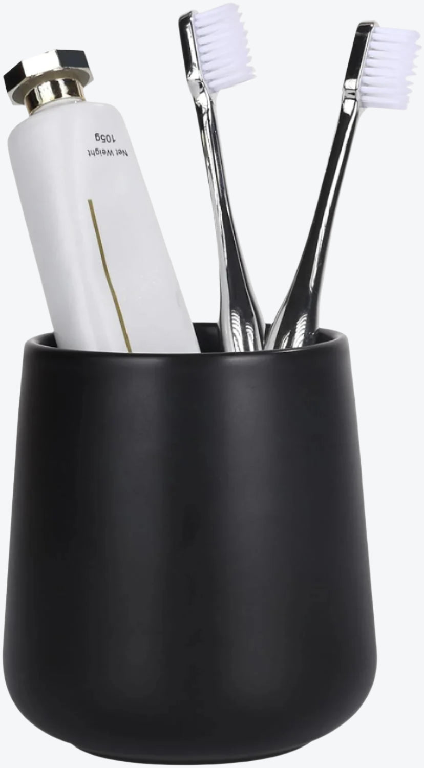 Black toothbrush holder with white toothbrushes and a white bottle on a white background